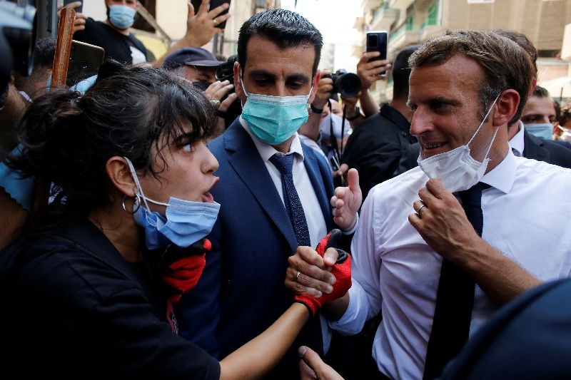 French President Emmanuel Macron listens to a resident as he visits a devastated street of Beirut, Lebanon August 6, 2020. Thibault Camus/Pool via REUTERS